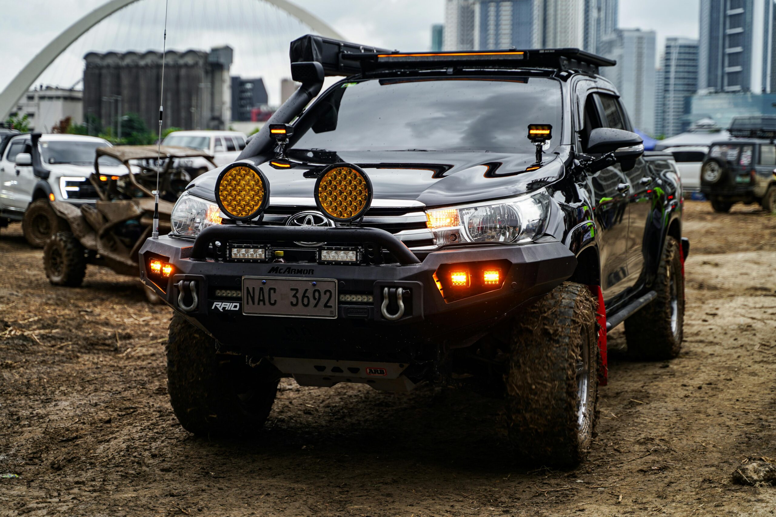 An off-road vehicle on a dirt road in Pasig City with a city skyline backdrop.