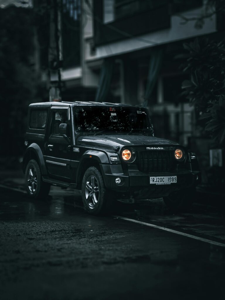 A Mahindra Thar captured on a rainy street at night, showcasing its rugged design.