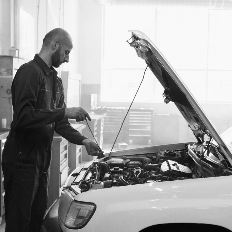 Mechanic in a garage performing engine maintenance on a vehicle.